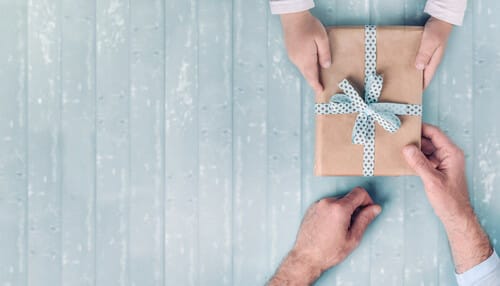 フランスのタッチを持つ青い木製の背景にギフト ボックスを持つ 2 つの手。 フランスのタッチを持つ青い木製の背景にギフト ボックスを持つ 2 つの手。