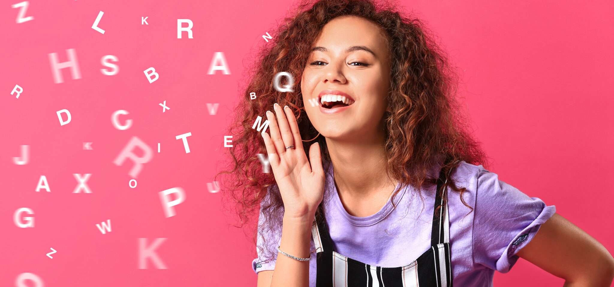 フランスのピンクの背景に文字を吹き飛ばす巻き毛の女性。