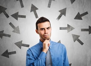 フランスで、さまざまな方向を指す矢印の前に男性が立っています。 shutterstock_275700443