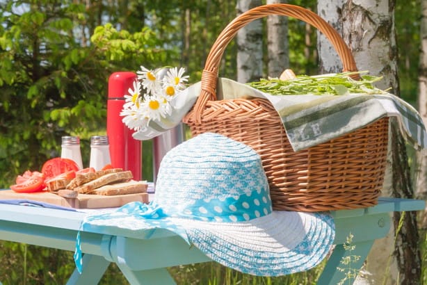 フランスから来た、食べ物の入ったバスケットと帽子を備えたピクニックテーブル。