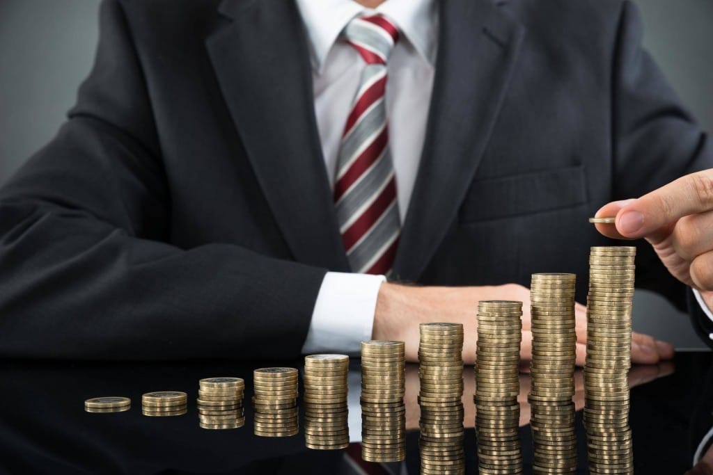 フランスで、スーツを着た男性が硬貨の山の上に硬貨を置いている。 shutterstock_316983149