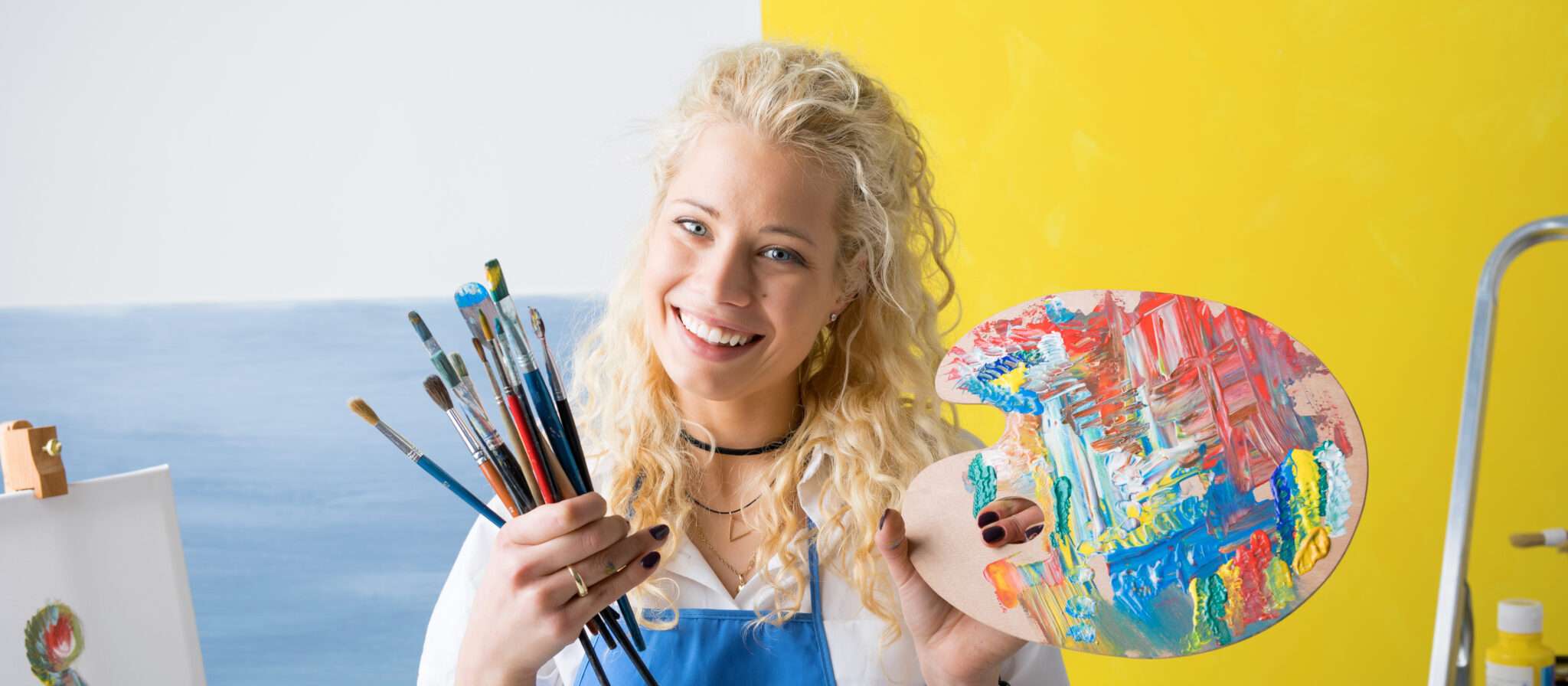 パレットと絵筆を持ったフランス出身の金髪の女性。