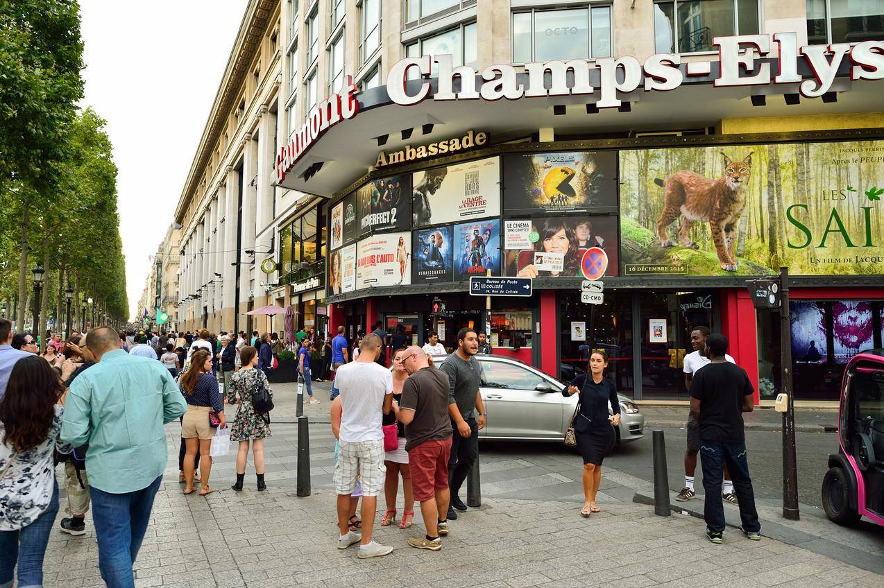フランスのシャンゼリゼ通りの店の前に立つ大勢の人々。