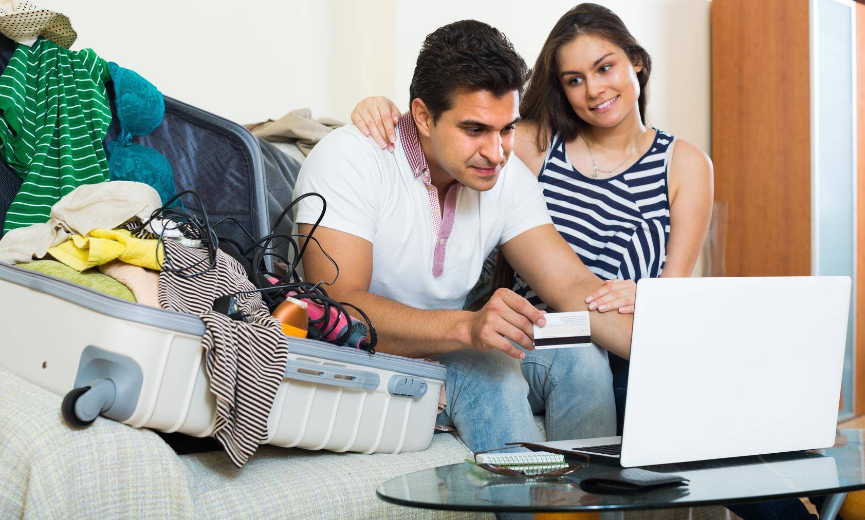 荷物とラップトップを持ってソファに座っている男性と女性。おそらくフランスへの旅行を計画しています。