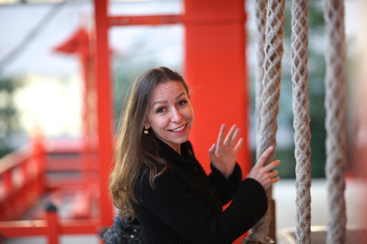 フランスの赤い鳥居の横に立つ黒いジャケットを着た女性。