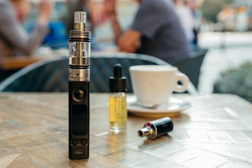 フランスのコーヒーカップの隣のテーブルに置かれている電子タバコ。