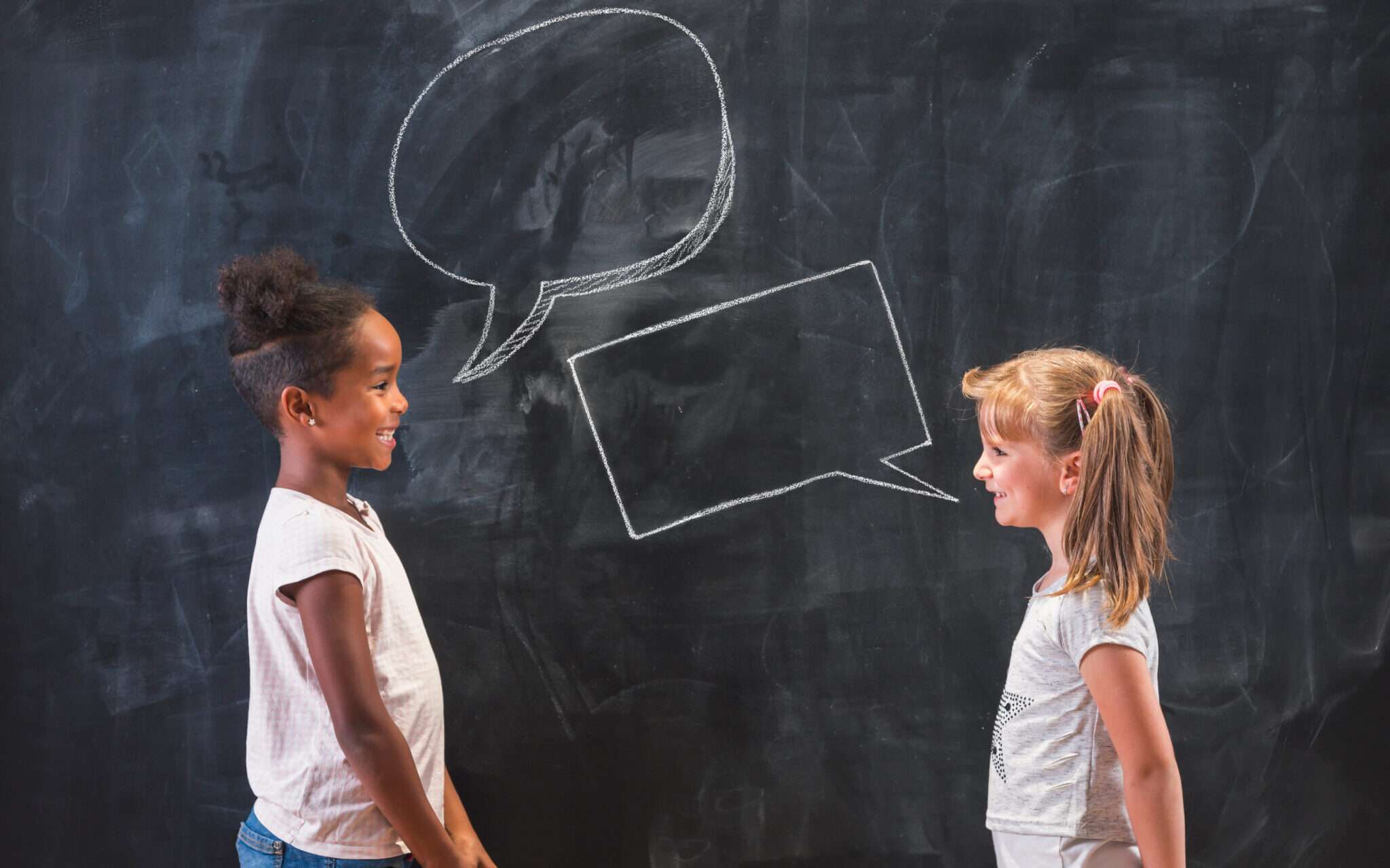 フランスについて吹き出しのある黒板の前で話している 2 人の女の子。