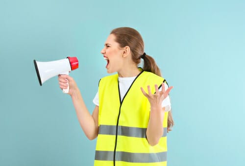 メガホンに向かって叫ぶベストを着たフランス人女性。