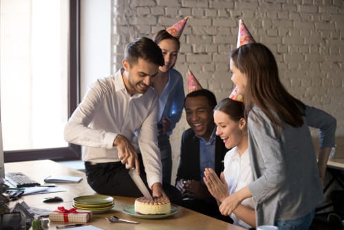 フランスのオフィスで誕生日ケーキをカットする人々のグループ。