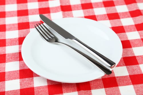 フランスを思わせる赤と白のチェック柄のテーブルクロスに、フォークとナイフがセットされた白いお皿。