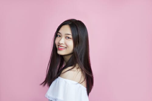 フランスのピンクの背景の前でポーズをとる若いアジア人女性。