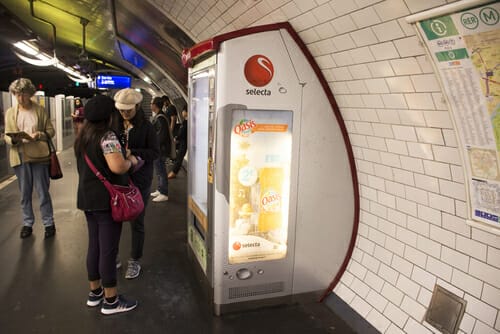 フランスの地下鉄駅の自動販売機の隣に立つ 2 人。