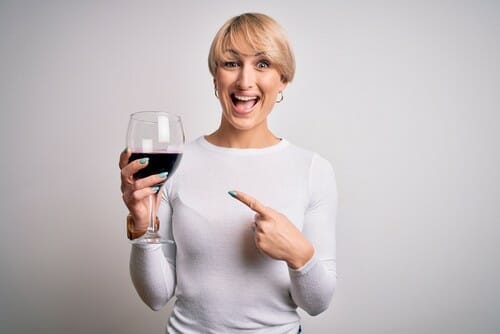 フランスから来た女性がワインの入ったグラスを持ってそれを指差しています。