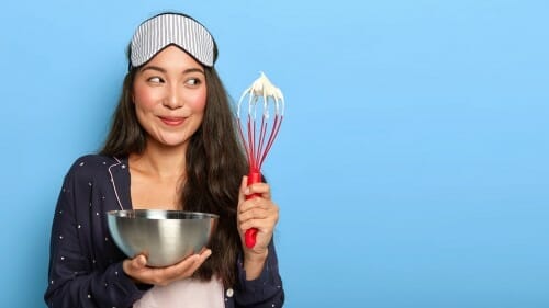 泡立て器とアイシングの入ったボウルを持つフランスの若い女性。 泡立て器とアイシングの入ったボウルを持つフランスの若い女性。