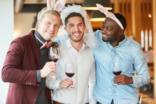 フランスの三人の男性がウサギの耳を付けてワイングラスを持っています。