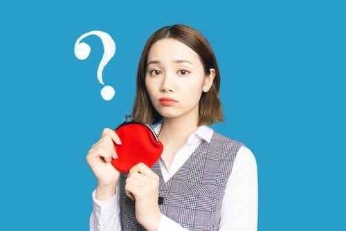 フランス (フランス) で、疑問符の付いた赤い財布を持つ女性。