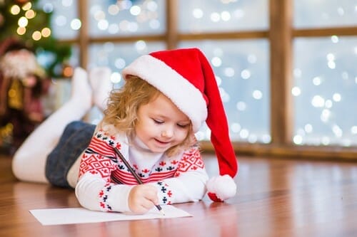 フランスでサンタ帽子をかぶって手紙を書く少女。