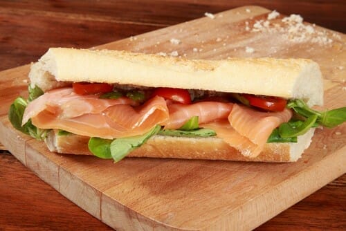 フランスの雰囲気を感じられる木のまな板にスモークサーモンのサンドイッチ。 フランスの雰囲気を感じられる木のまな板にスモークサーモンのサンドイッチ。