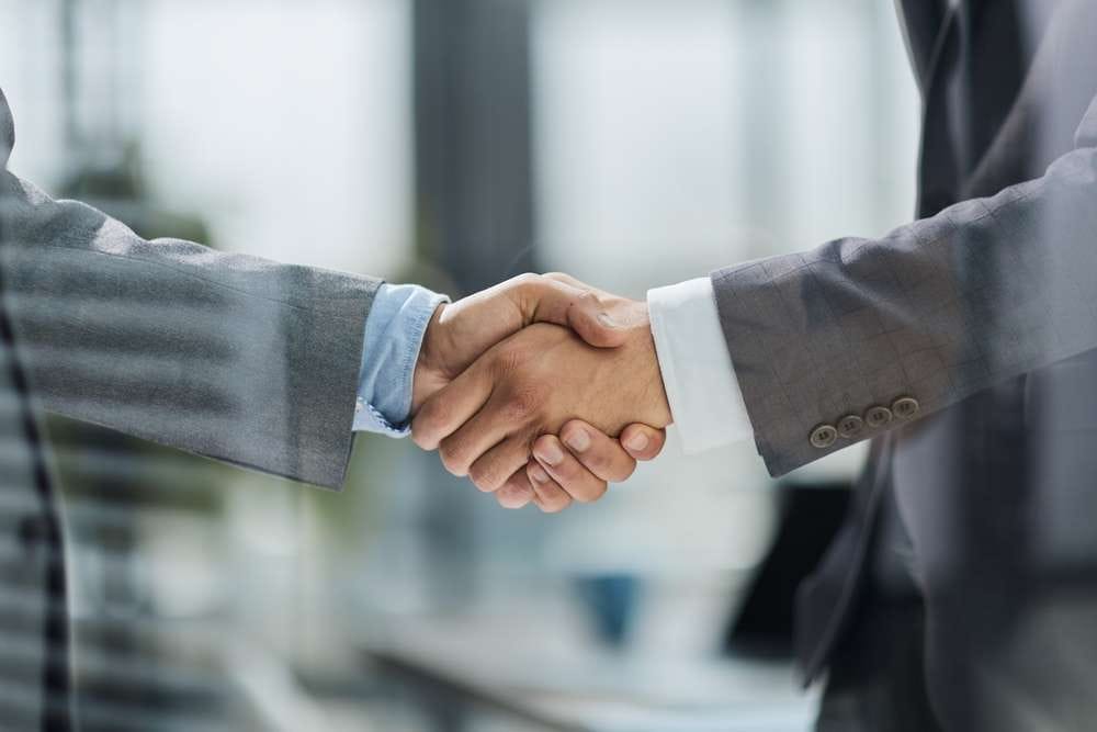 ビジネス服を着た二人がオフィスで握手しており、合意やパートナーシップを象徴しています。背景には大きなガラス窓があり、そこからぼんやりとした街並みが見え、フランスでのビジネス会議の洗練された雰囲気を醸し出しています。 ビジネス服を着た二人がオフィスで握手しており、合意やパートナーシップを象徴しています。背景には大きなガラス窓があり、そこからぼんやりとした街並みが見え、フランスでのビジネス会議の洗練された雰囲気を醸し出しています。