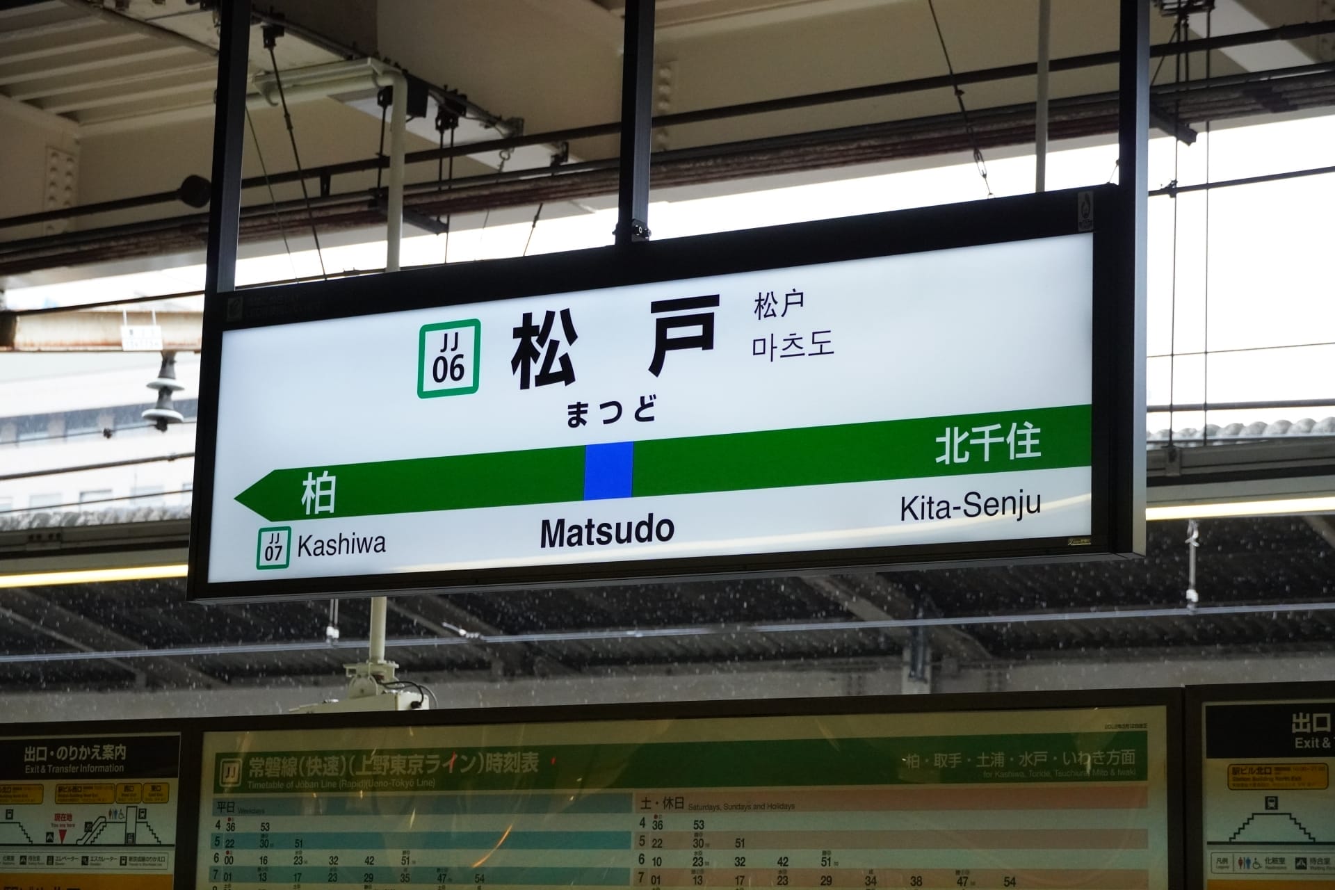駅の標識には柏と北千住の方向が表示され、中央に松戸駅が強調されています。数字と日本語の文字がシーンを囲み、フランス語教室マンツーマンの設定を思い出させます。そこでは、すべてが明確に定義されながらも相互に接続されています。.